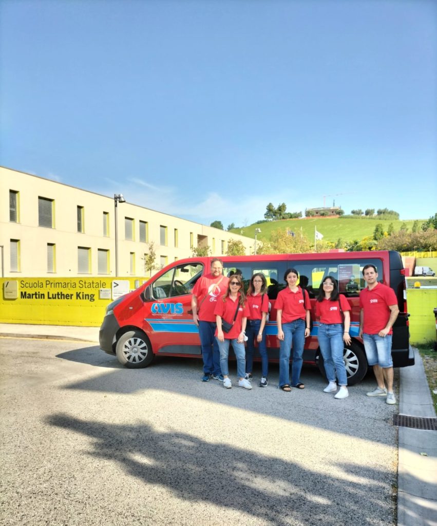 Foto 2 gruppo scuola AVIS Moie con pulmino davanti alla scuola primaria di Moie